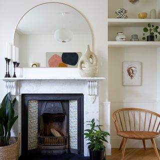 A white-painted living room with a marble fireplace and an arched mirror above it