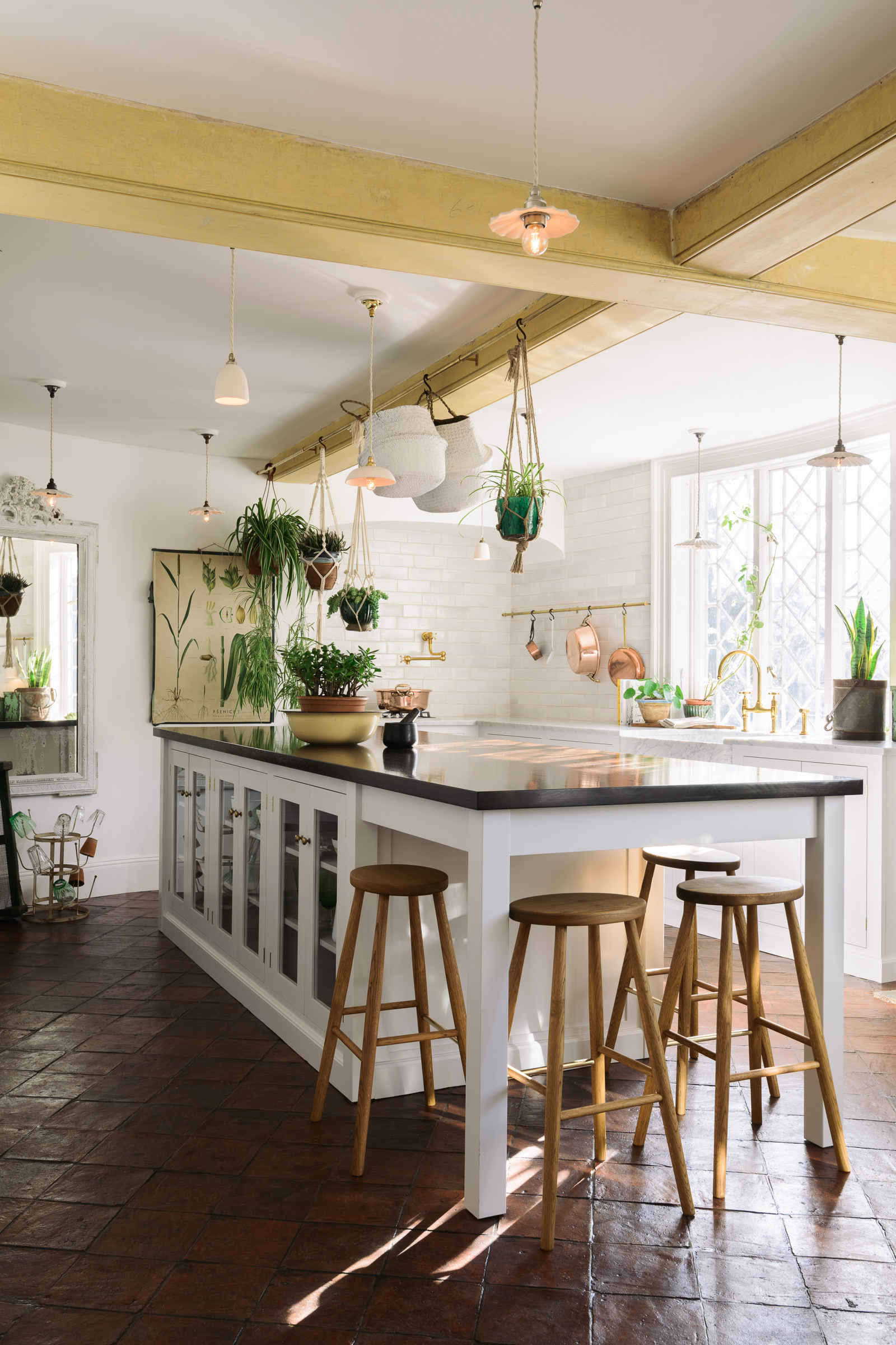 An open plan white kitchen with contrasting dark kitchen island work surface and tiled floor.