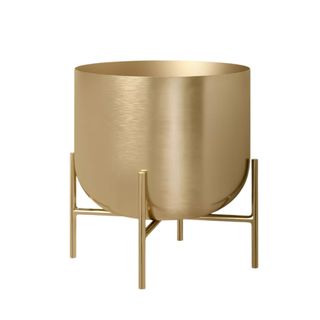 A brushed gold curved planter with four thin legs at the base