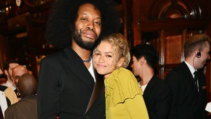 Zendaya poses with Jeremy O Harris at an event wearing a vintage sweater and tall boots