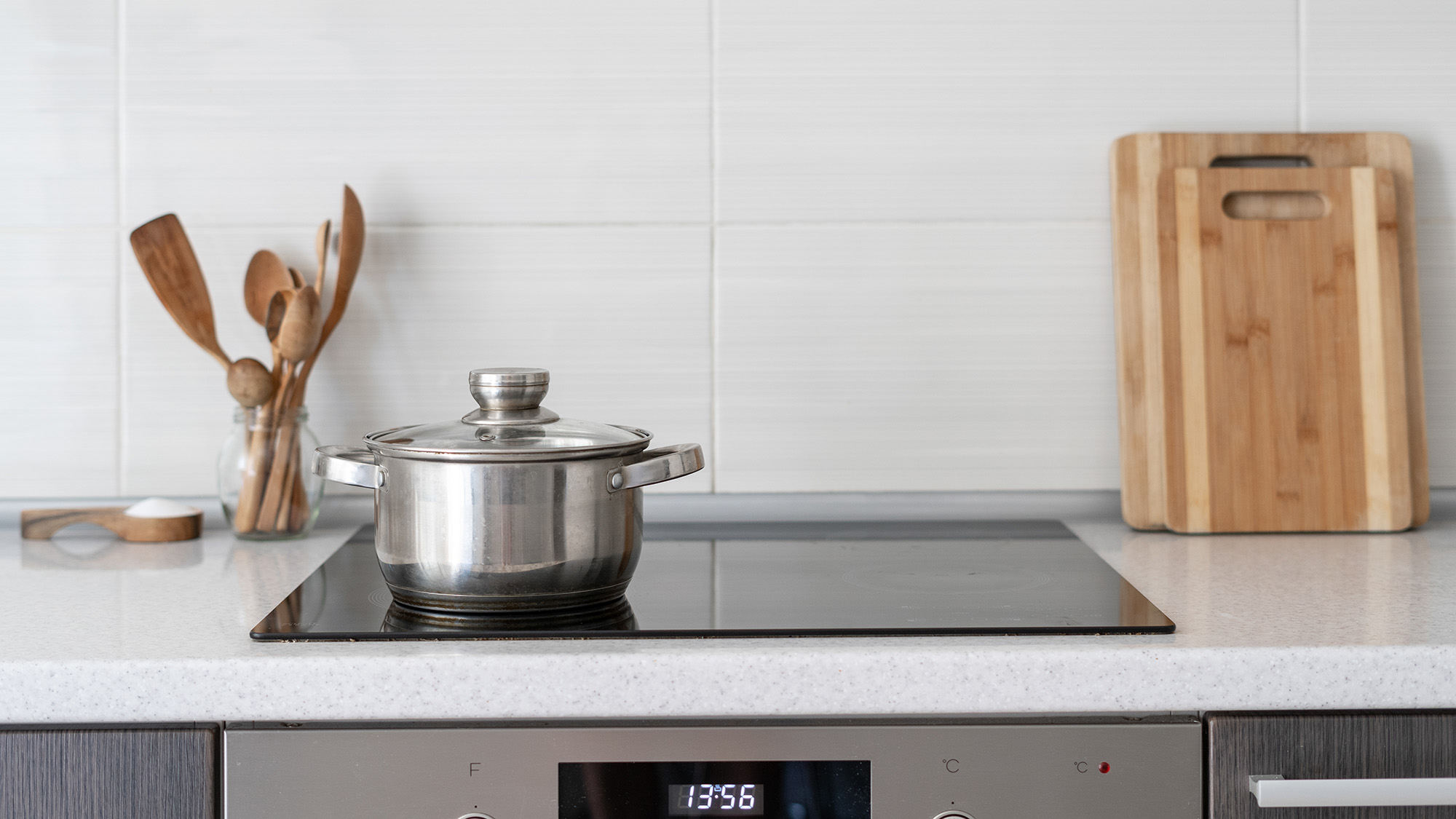 Black ceramic induction stove with timer on control panel and saucepan on top