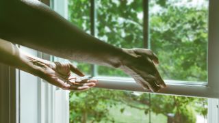 hands opening white sash window