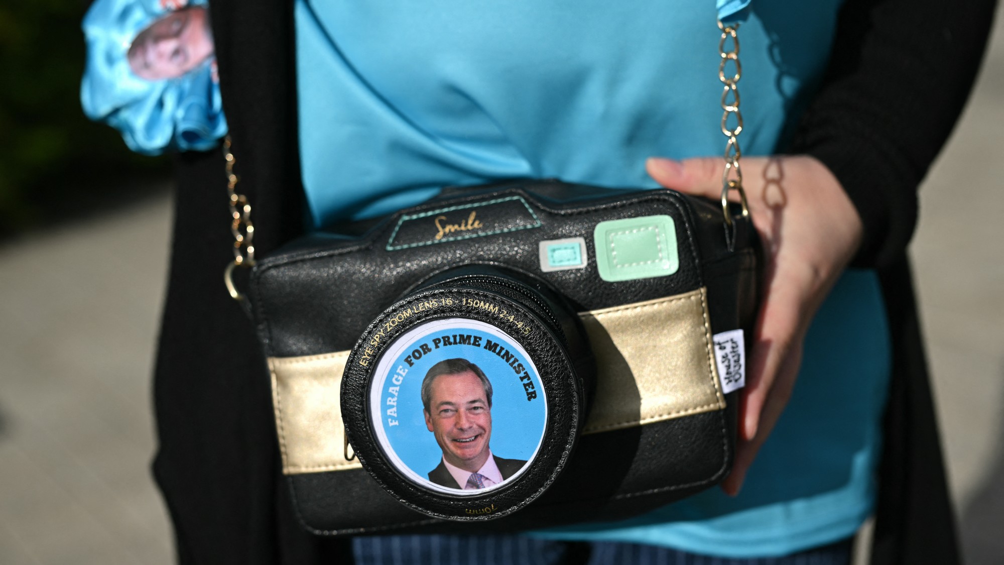 Someone carrying a shoulder bag with a Nigel Farage badge imposed on the front