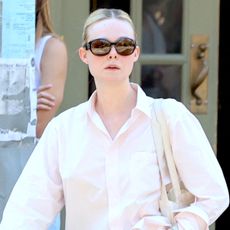 Elle Fanning wearing an oversized button-down shirt with baggy tan chinos and The Row soft loafers