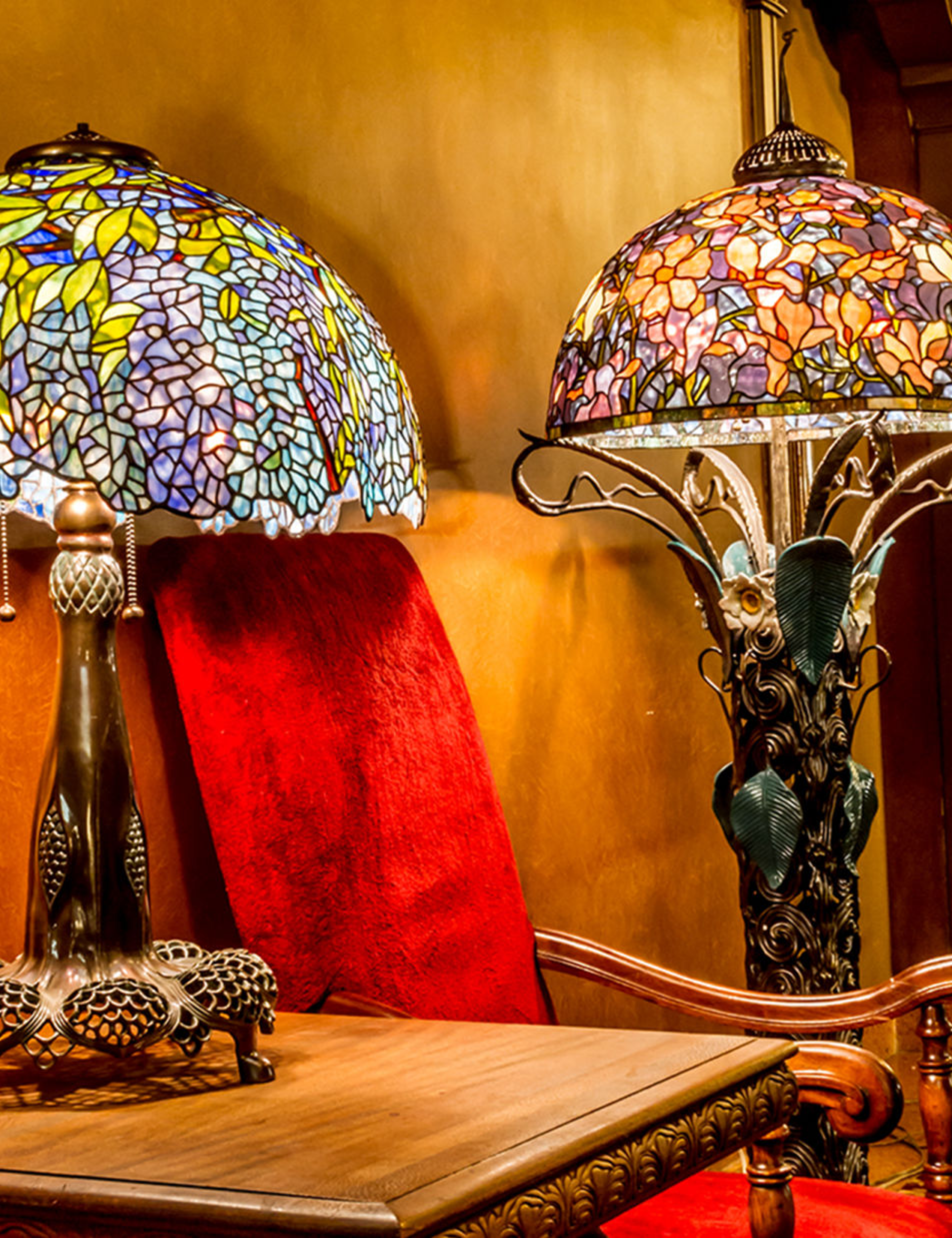 Two Tiffany lamp reproductions pictured alongside antique furniture