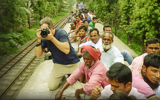 Photographer on top of a train with other passengers in India