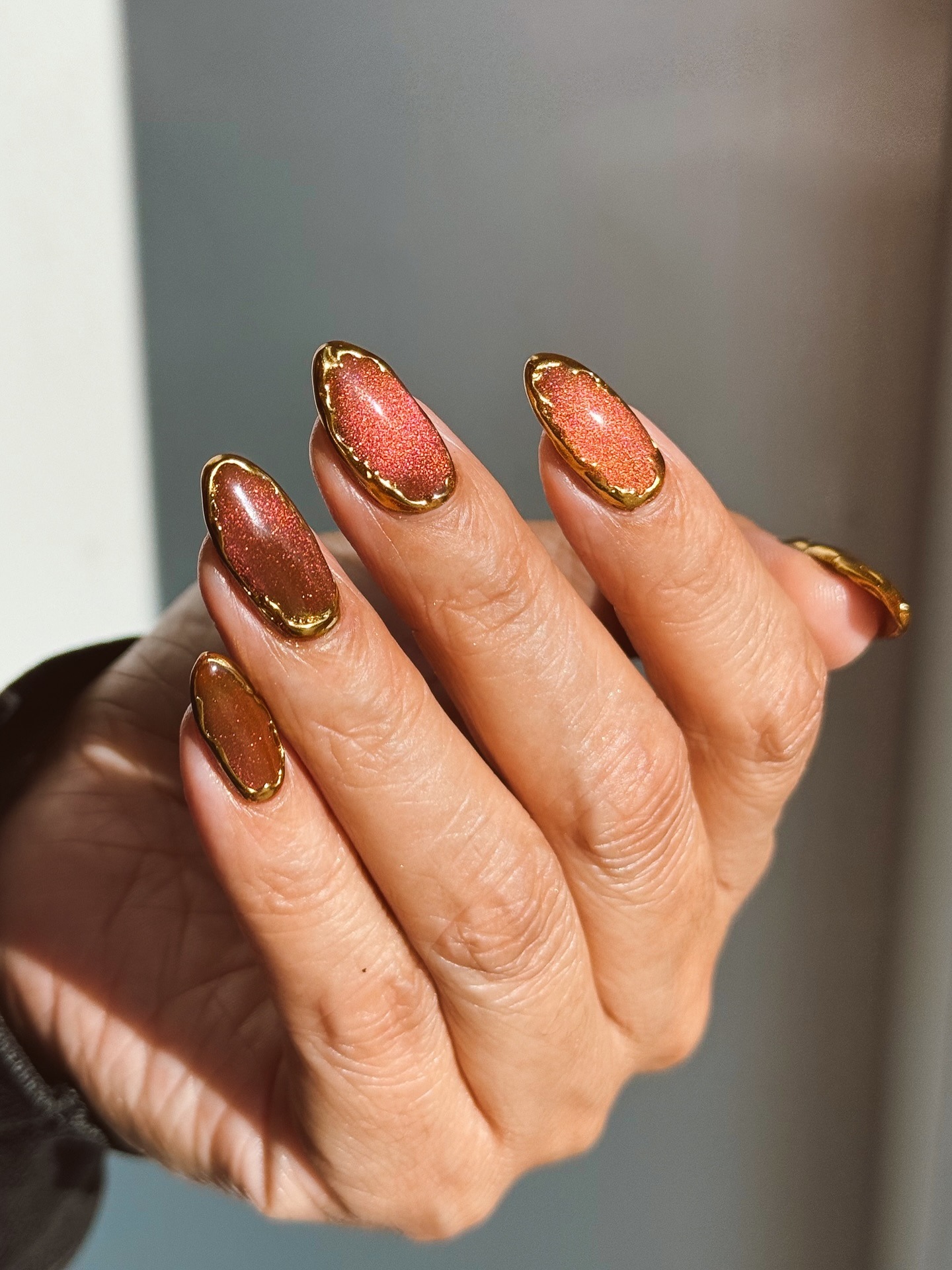 A warm, cinnamon-toned manicure with gold detailing