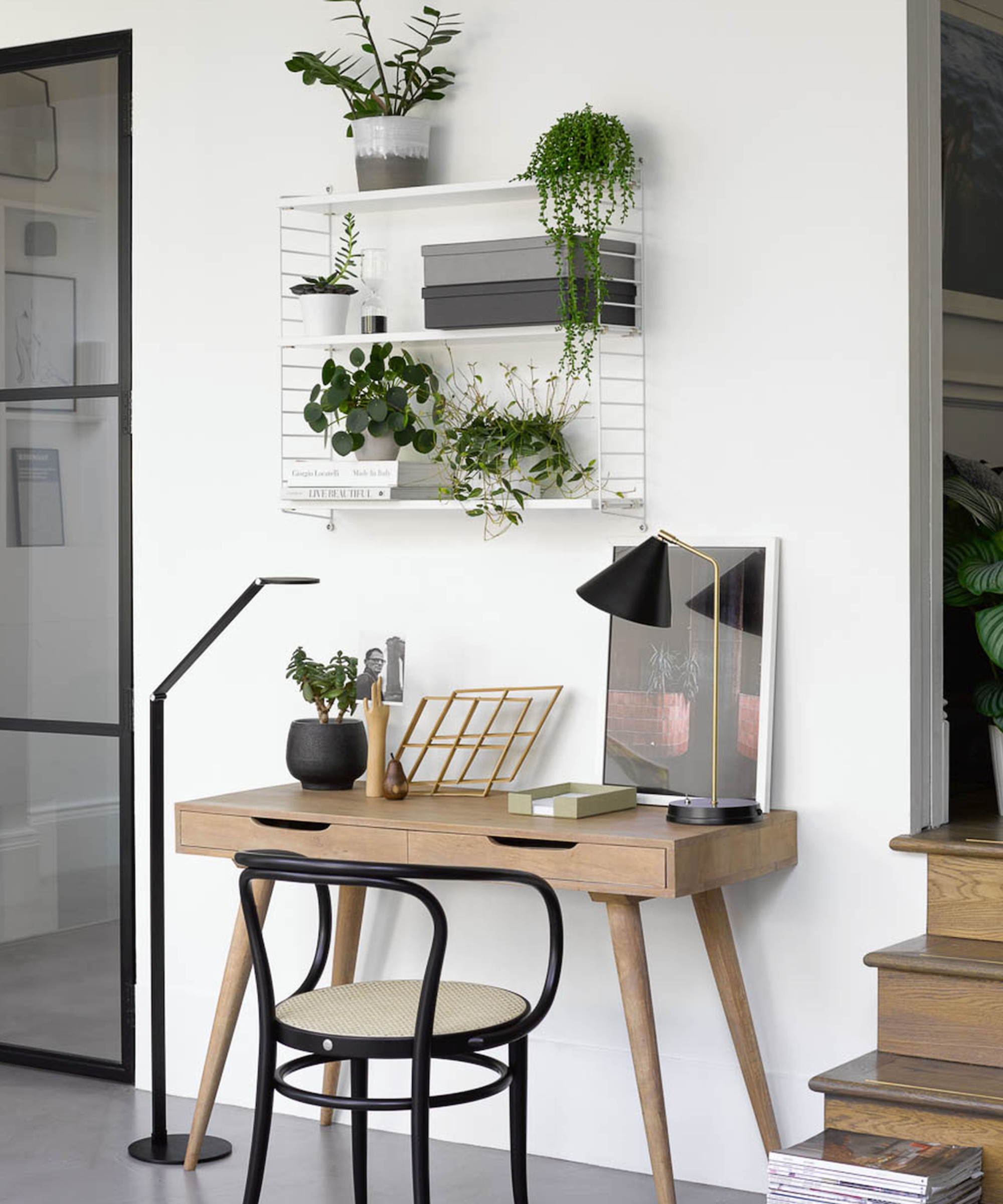 smal modern wooden desk with black and gold table lamp and black low floor lamp to side of desk