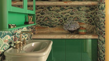 a green bathroom with a patterned wallpaper, a green gloss cabinet and a light green pedestal basin