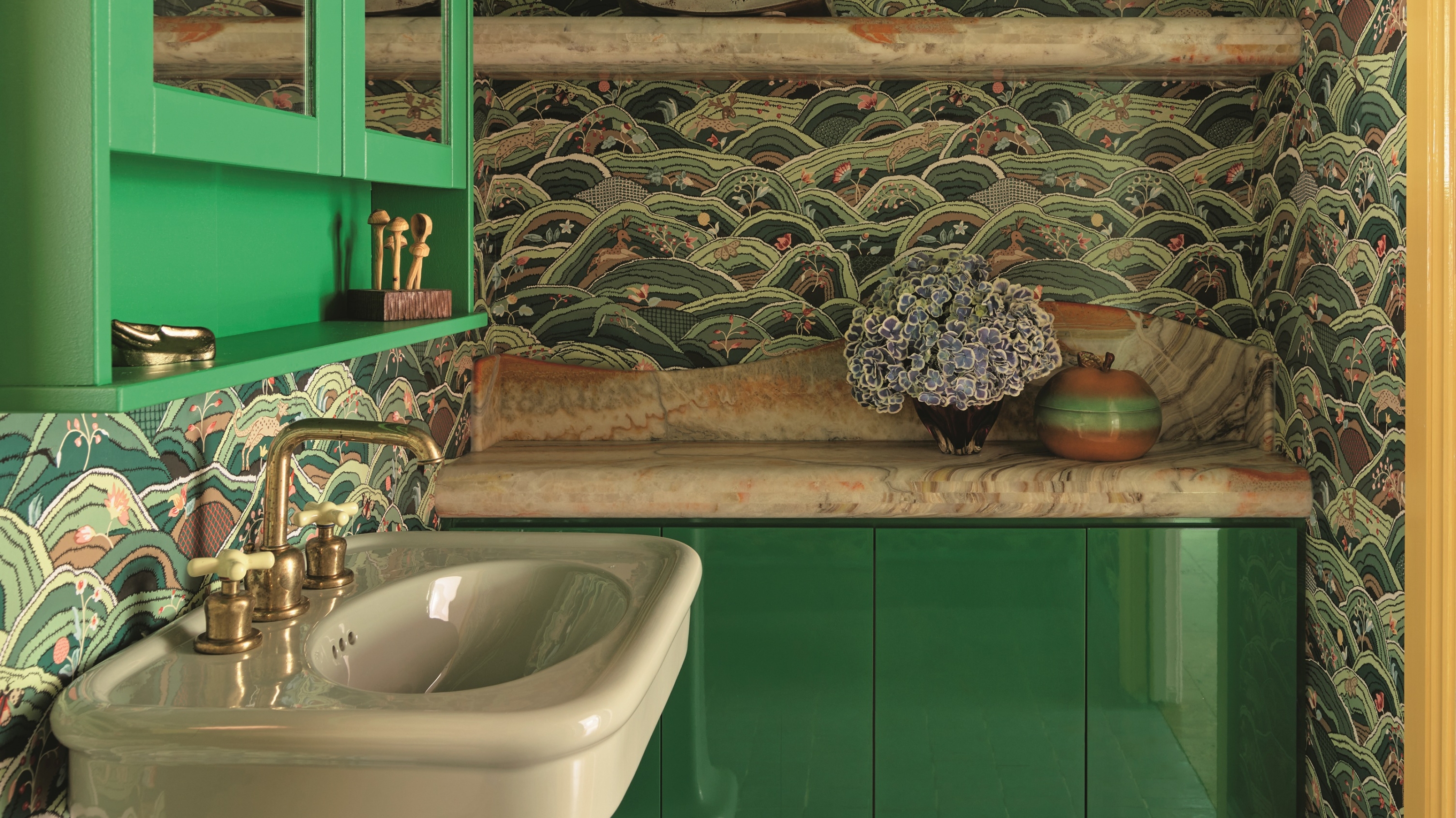 a green bathroom with a patterned wallpaper, a green gloss cabinet and a light green pedestal basin