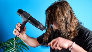 the heist 3.0 men's hair dryer in black with a bright green ring and magnetic attachment photographed against a blue background