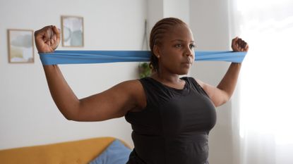 Woman doing arm exercises in living room with a loop resistance band