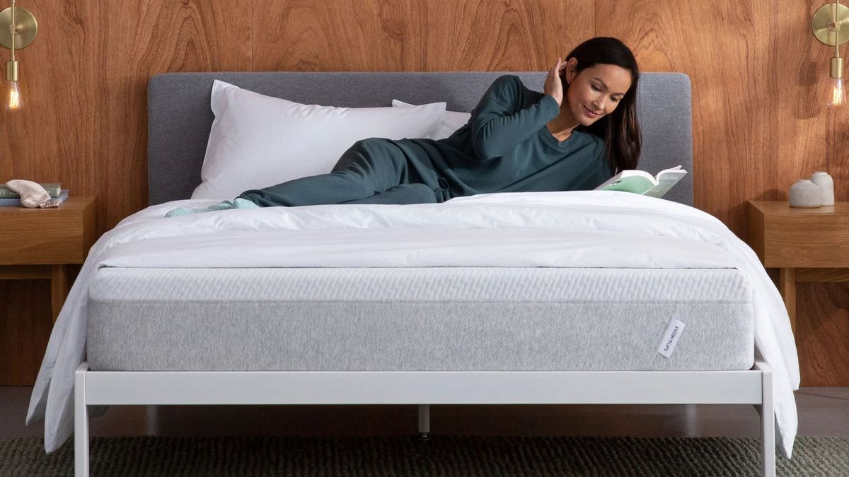 Tuft and Needle Original mattress with a woman laying across while reading a book in her bedroom