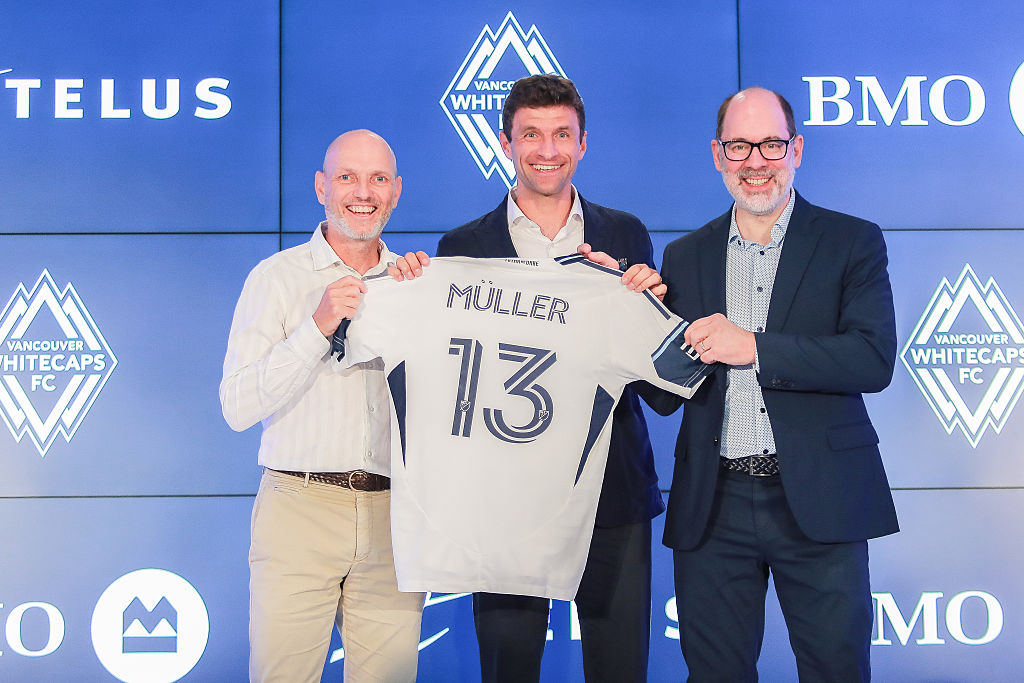 Thomas M&amp;uuml;ller poses with his jersey alongside Jesper S&amp;oslash;rensen Whitecaps FC head coach and Axel Schuster, Whitecaps FC CEO and sporting director