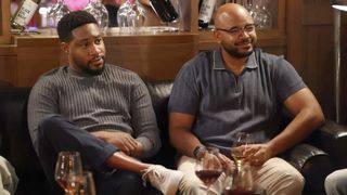 Aaron Jennings as Anthony and Justin Cunningham as Wyatt sitting in front of wine glasses in Grand Crew season 2