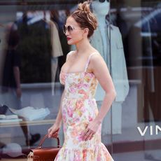 J.lo wears a floral dress with circular sunglasses.
