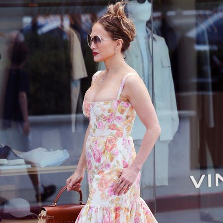J.lo wears a floral dress with circular sunglasses.