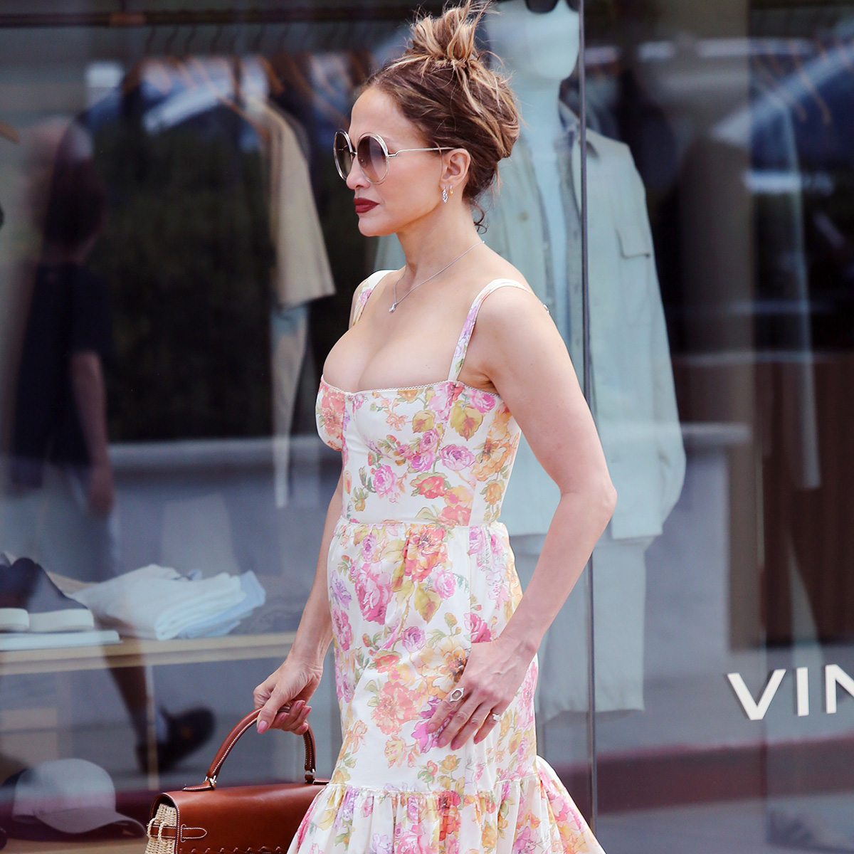 J.lo wears a floral dress with circular sunglasses.