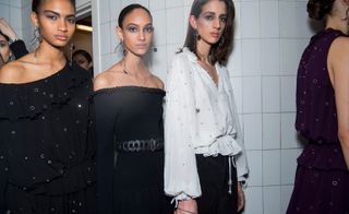 Two models are seen wearing cold-shoulder and bardot tops in black. Another wears a white blouse with ties
