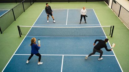 A group of four young adults play pickleball.