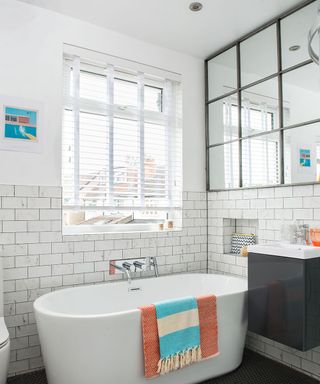 White bathroom with large window and large window mirror over bath