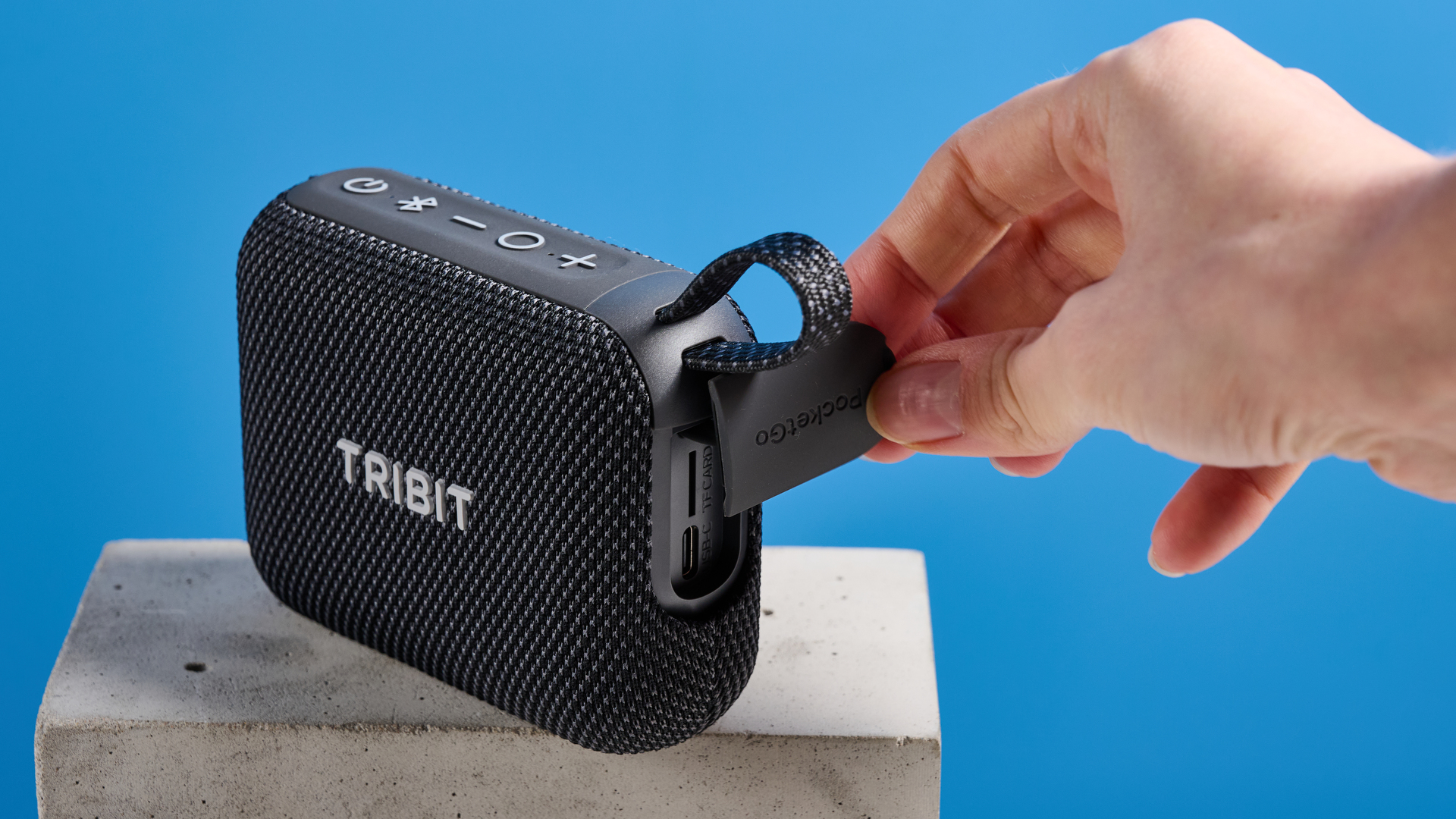 The Tribit PocketGo speaker in black photographed on a blue background.