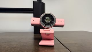 The pink Razer Kiyo V2 on a wooden desk, with the lens pointing to the centre and up