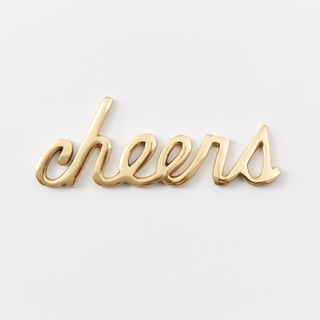 A brass cursive 'cheers' sign