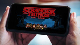 Henkilö pelaa Stranger Things -peliä mobiililaitteella