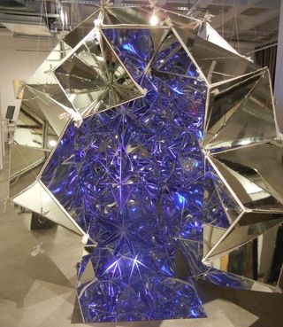An art installation that looks like s crystal. It has a gold exterior and a purple interior.