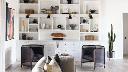 A living room with white walls, built-in shelving with decor and accessories, and two armchairs facing each other