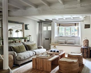 cozy, cottagey living room space rich with texture, neutral color palette with window bench seating, sofa, wooden coffee tables and textured low seats in natural fabrics, woven baskets and storage chests, textured rug