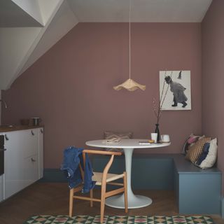 kitchen with blue box seating and white round table and pink walls