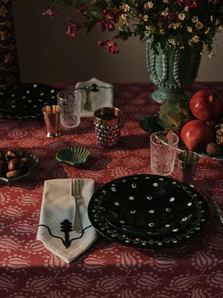 Table set up for a meal with dark tablecloth and plates