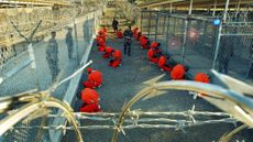 Al-Qaida and Taliban detainees kneel in orange jumpsuits at Camp X-Ray at Guantanamo Bay in 2002