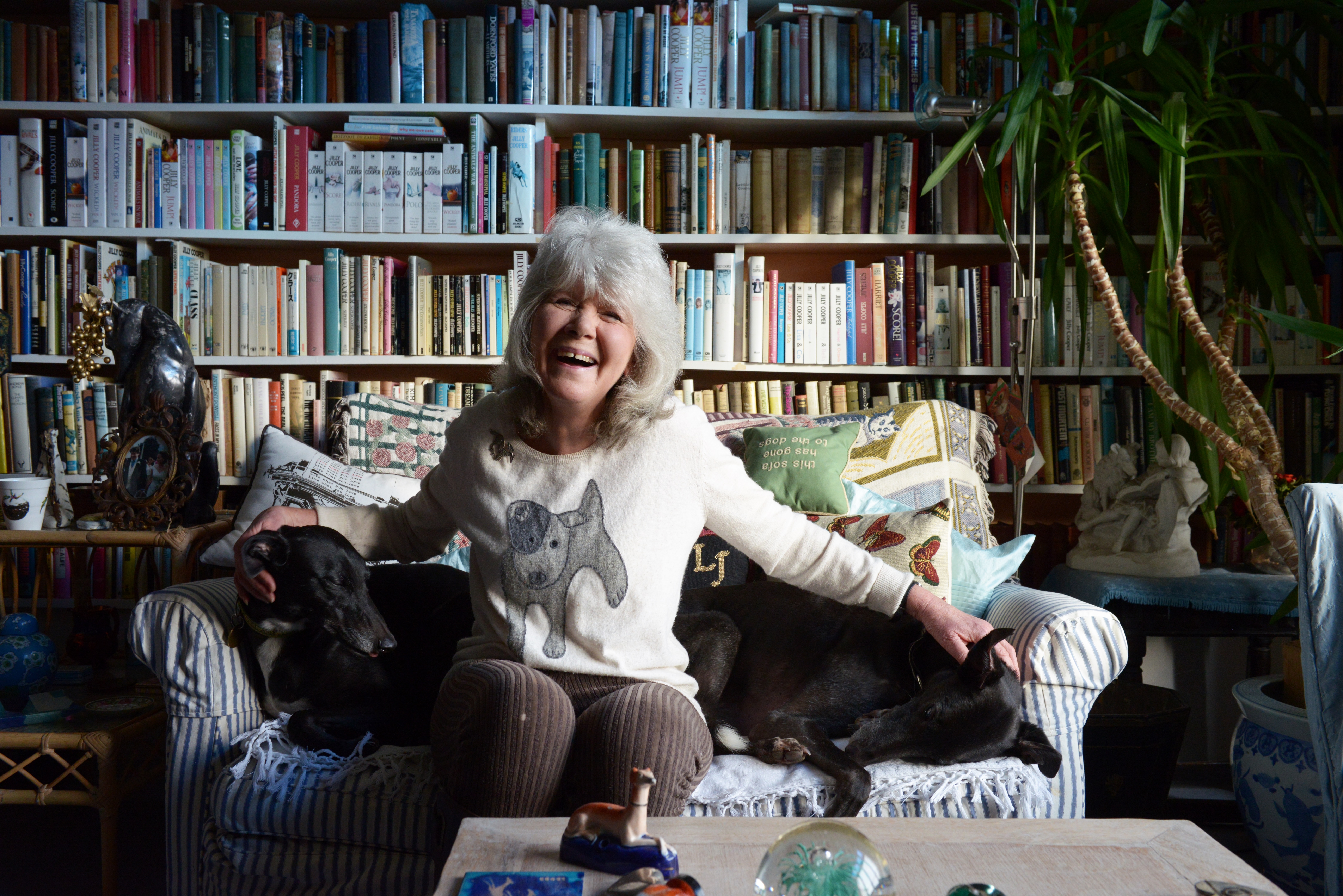 Jilly Cooper sitting on a sofa with her two dogs