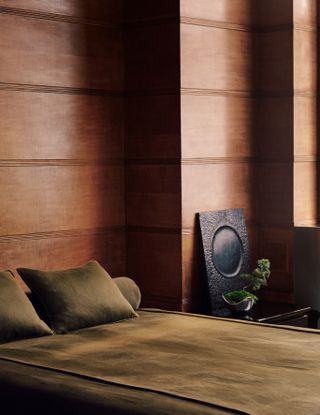 Japandi-style living space with rich walnut wood paneling, low-slung furniture, minimalist plants, and pops of moss green