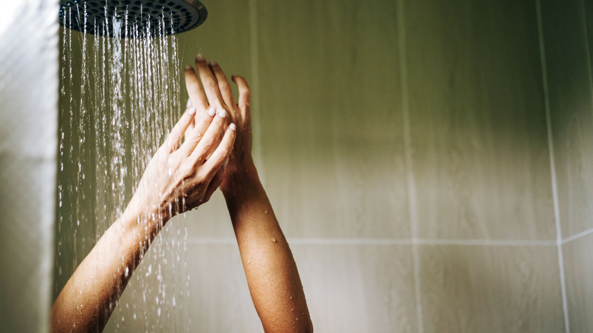 image of a womans hands underneath a shower head