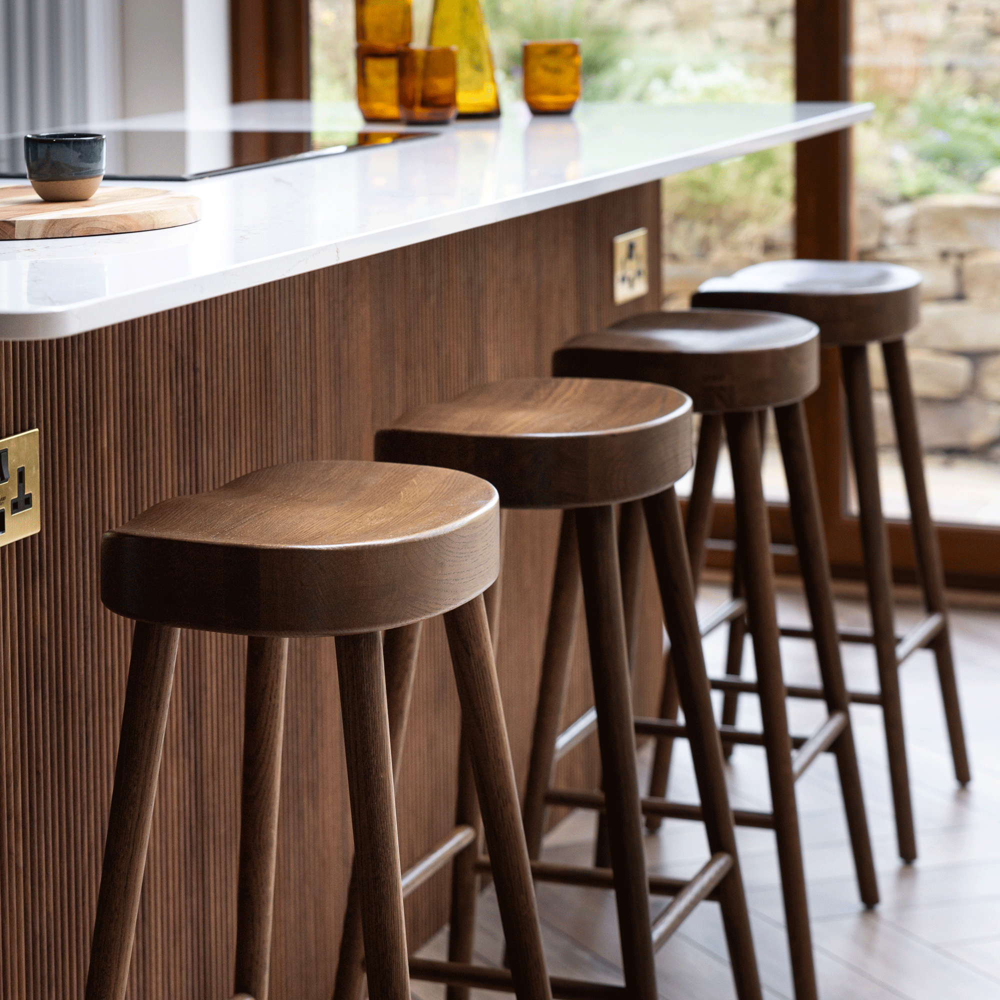 a kitchen with a row of wooden bar stools beside a kitchen island