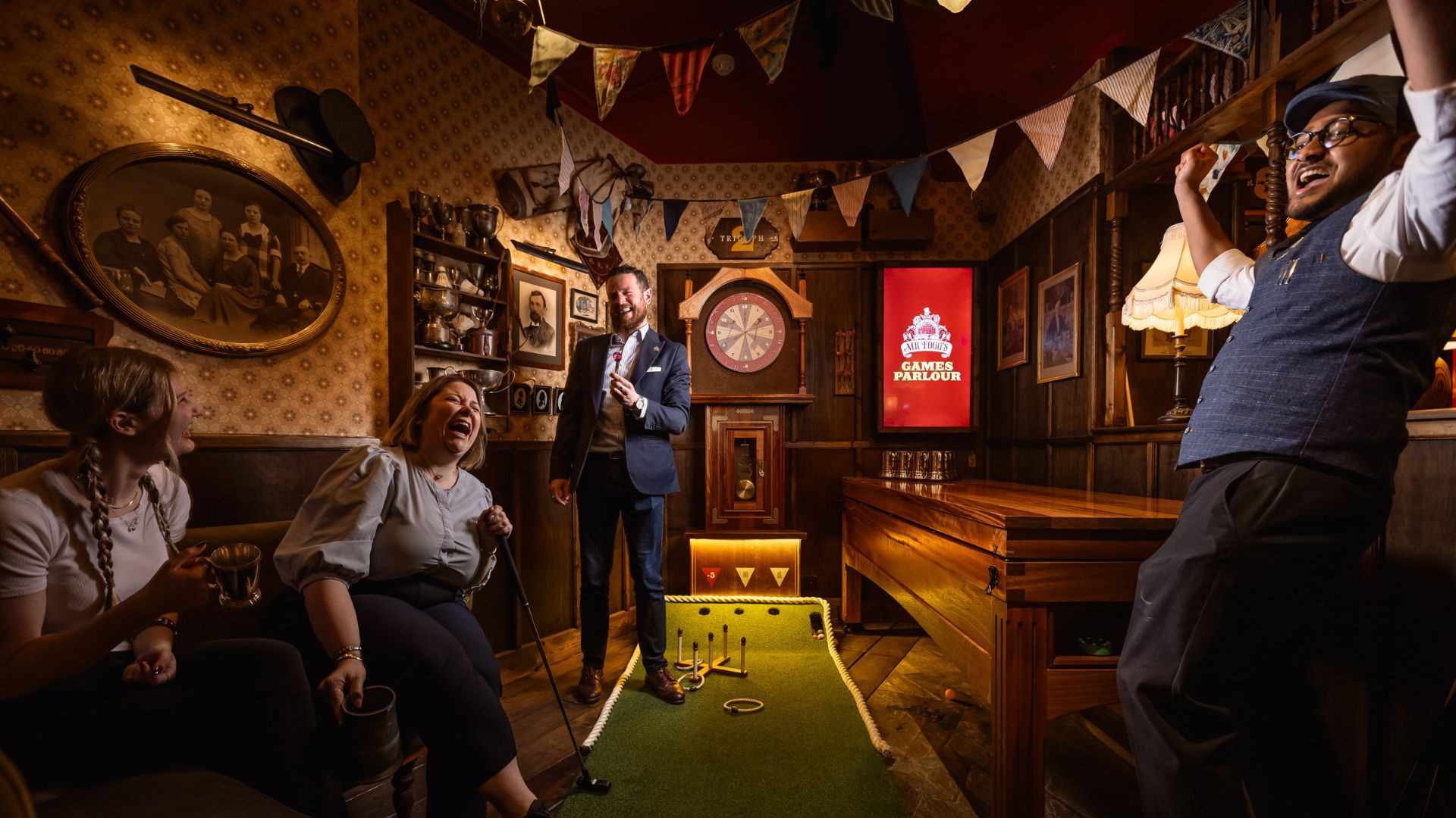 an image of two men and two women playing one of the games in the parlour, with one man on the far right celebrating a win