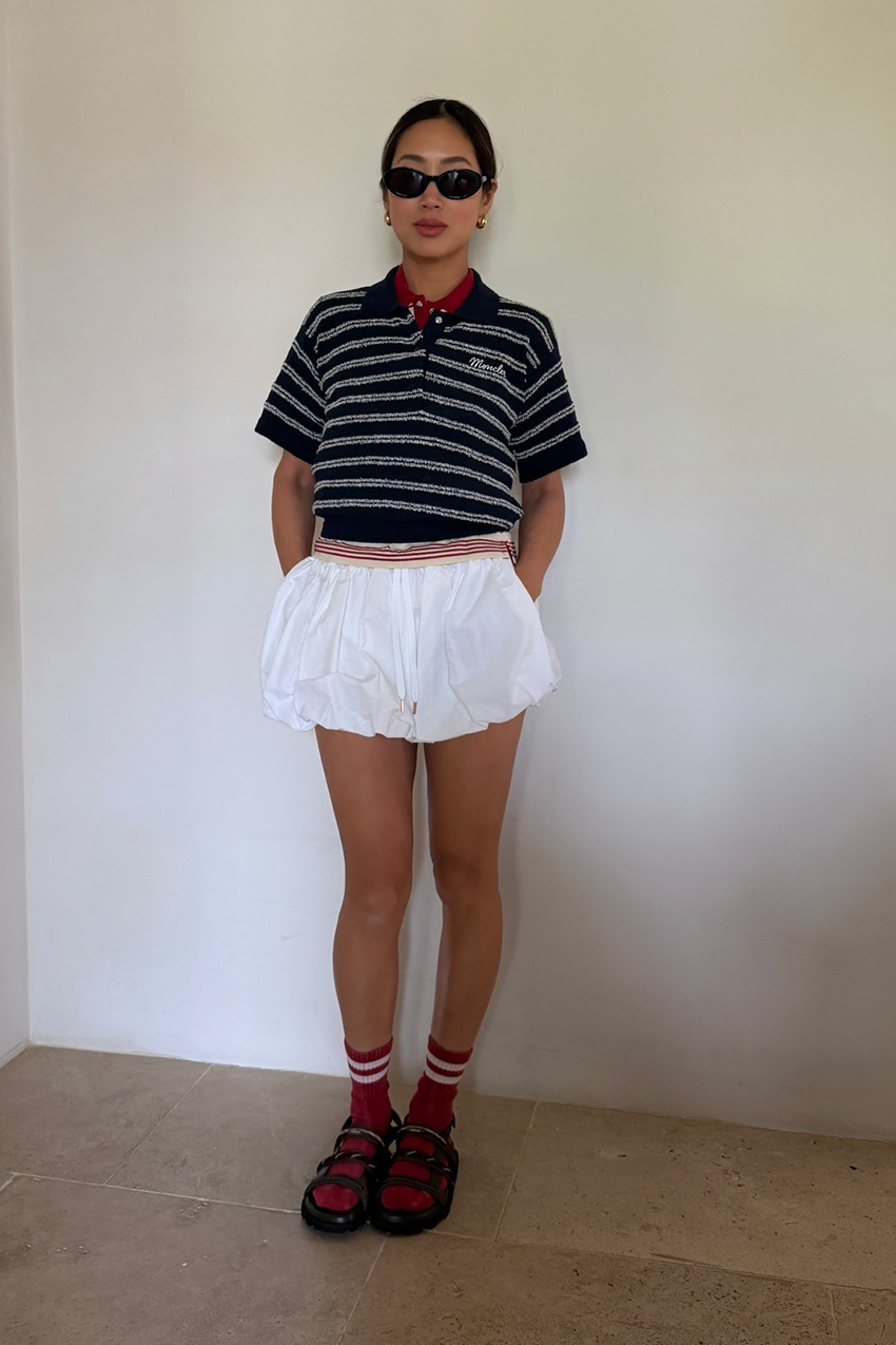 a woman wearing a striped polo shirt and white shorts