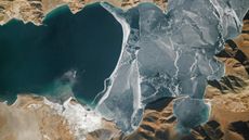 An astronaut photo of a section of a lake half covered in fracturing ice