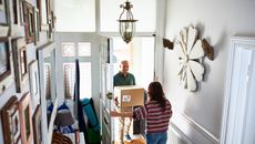 Delivery man giving parcels to woman in home hallway.