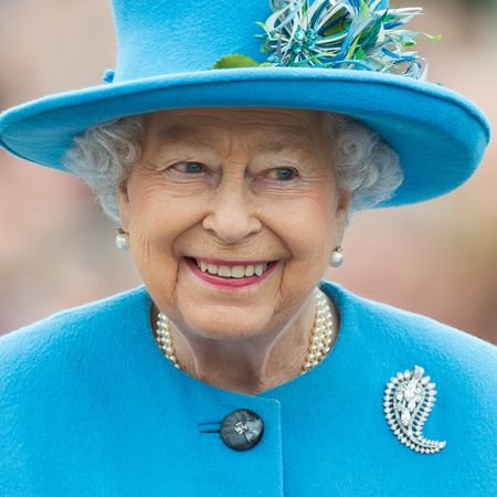 Queen Elizabeth smiling in a turquoise coat and hat