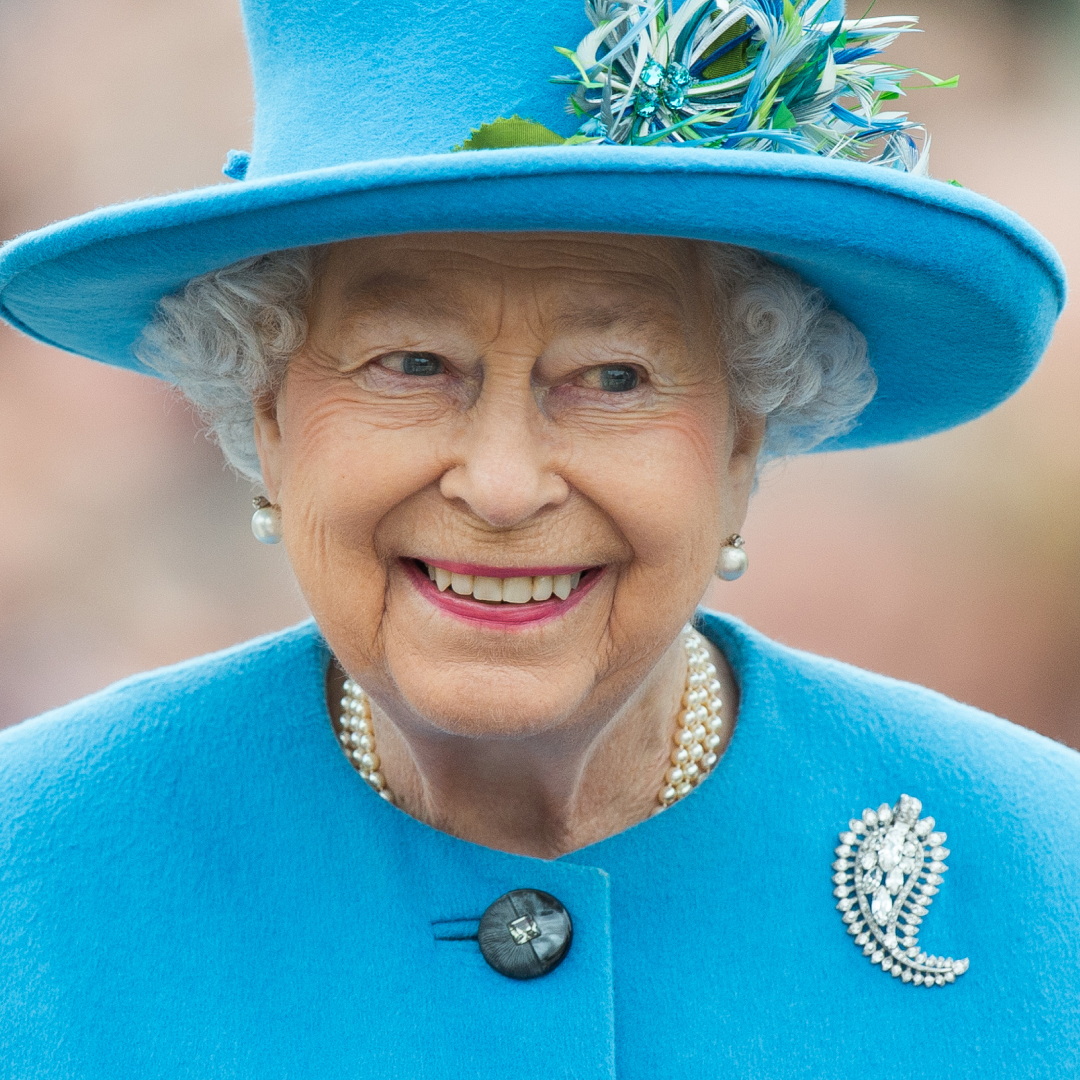 Queen Elizabeth smiling in a turquoise coat and hat
