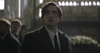 Bruce Wayne looking up at The Riddler in The Batman