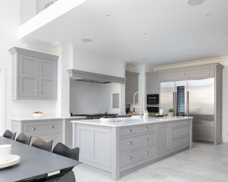 A white and gray open plan kitchen with double height ceiling.