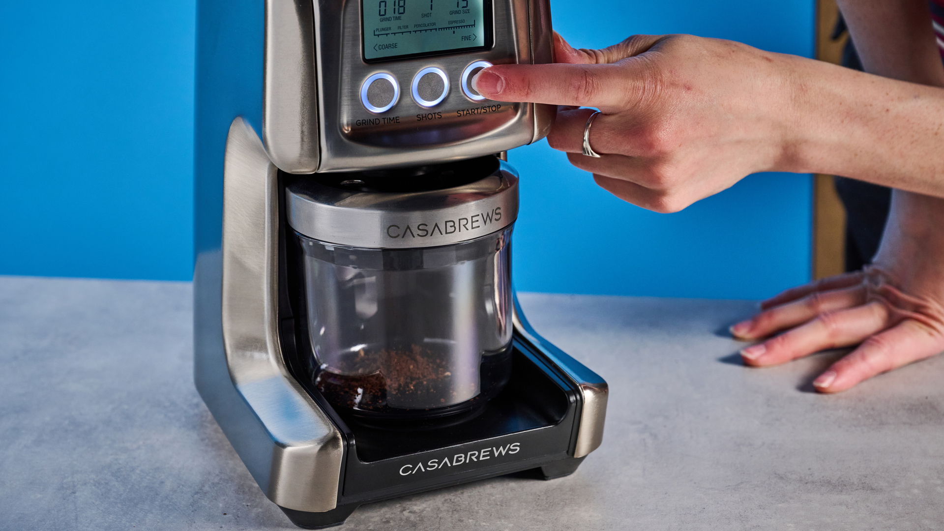the casabrews tornado coffee grinder in silver showing the LED screen, grind adjustment dial, and photographed against a blue background
