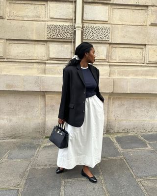 Marilyn in a white skirt with a black blazer and navy shirt