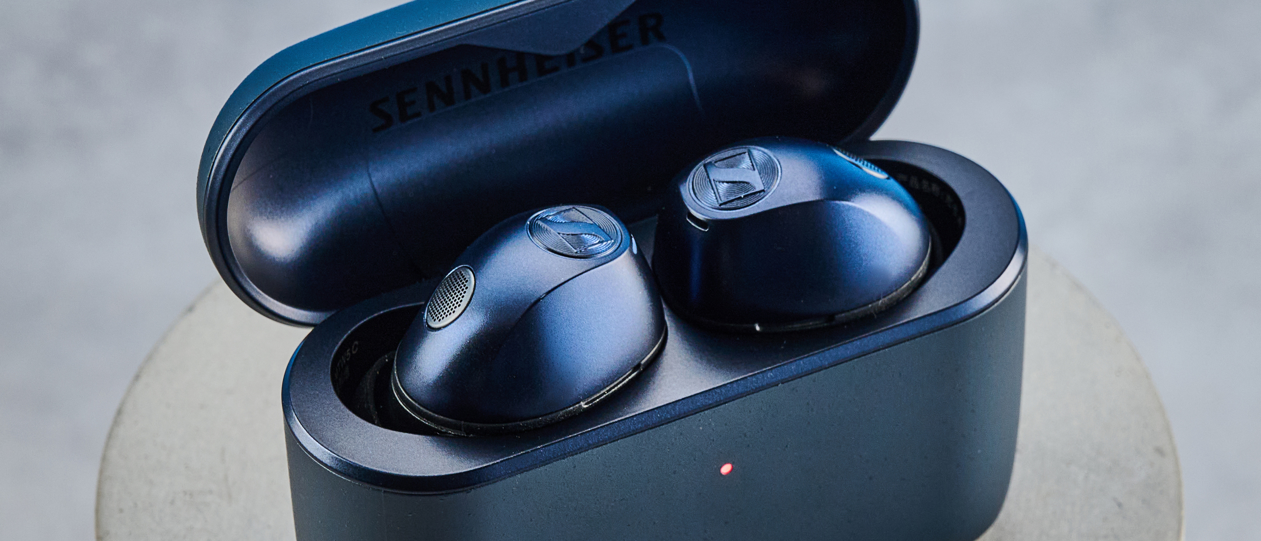 the sennheiser momentum 5 true wireless earbuds in navy photographed with the blue tom's guide background